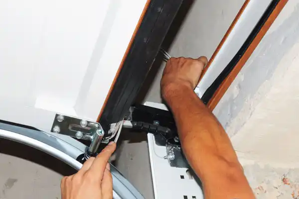 A [account_name] technician performing maintenance on a garage door roller.
